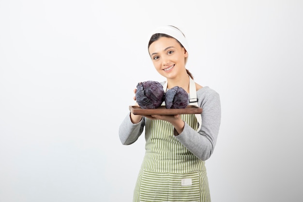 Изображение молодой улыбающейся домохозяйки, держащей тарелку фиолетовой капусты
