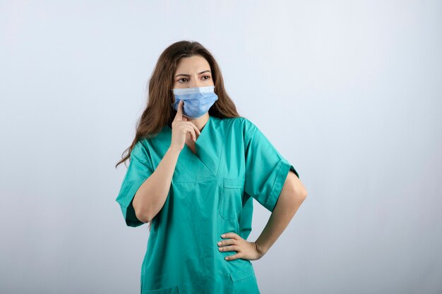 Image of a pensive beautiful nurse in green uniform looking away 