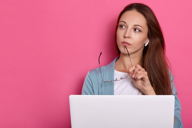 Image of pensive female posing against rosy wall.