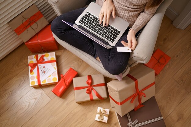 Image of pleased nice woman holding credit card with copy space using laptop