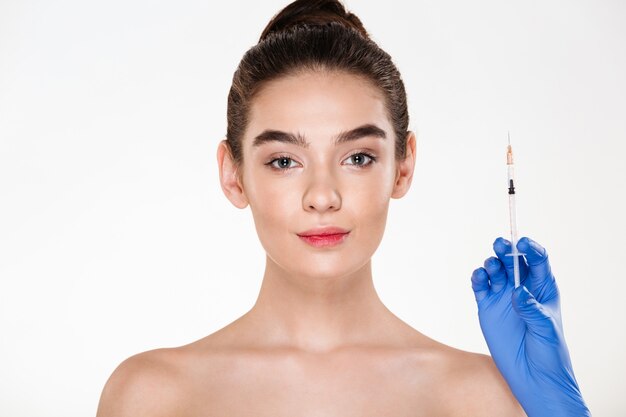 Image of pretty woman preparing for beauty injection made by doctor in latex gloves holding syringe with hyaluronic acid