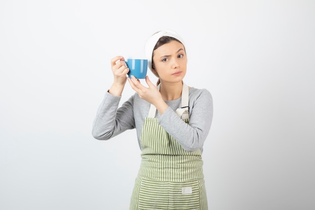 Image of a pretty young woman in apron holding a blue cup