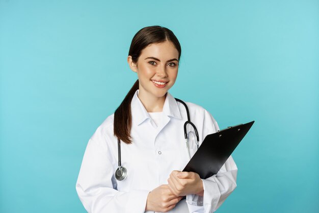 Image of professional woman doctor physician with clipboard writing listening patient at hospital cl...