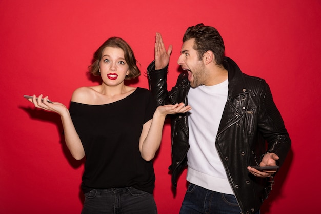 Image of Punk couple with smartphones quarrels between themselves