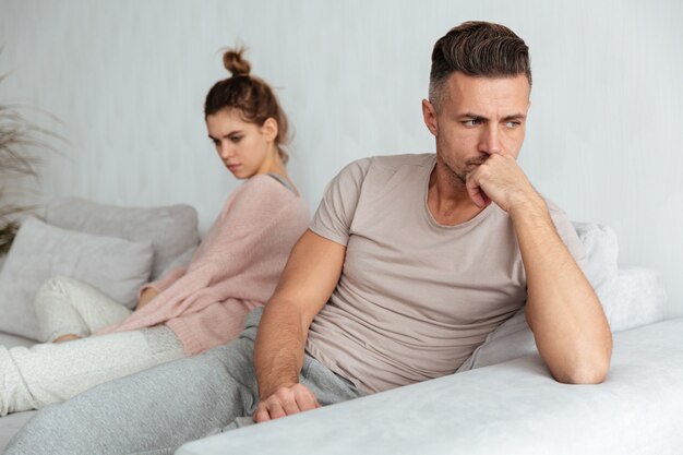 Image of Quarrelled lovely couple sitting separately on couch at home