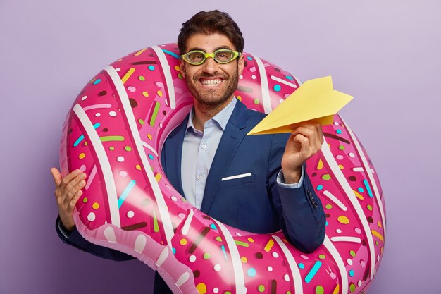 Image of satisfied European male director has toothy smile, carries handmade plane