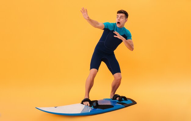 Image of Scared screaming surfer in wetsuit using surfboard like on wave