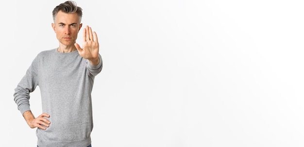 L'immagine di un serio uomo di mezza età tende una mano per impedirti di proibire qualcosa di brutto, accigliato e guarda