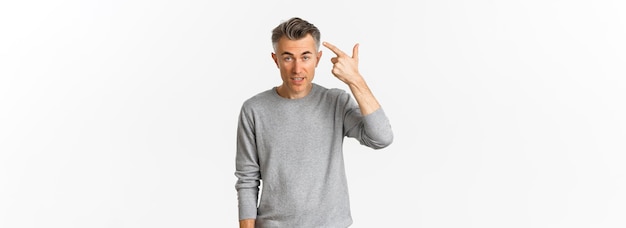 Free photo image of skeptical middleaged man scolding someone for stupid mistake pointing finger at head and looking annoyed standing over white background