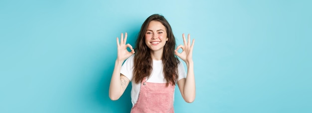 Free photo image of smiling brunette female model say yes showing okay signs in approval agree or praise good c