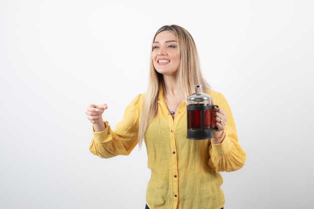 Image of a smiling pretty woman model holding a teapot .