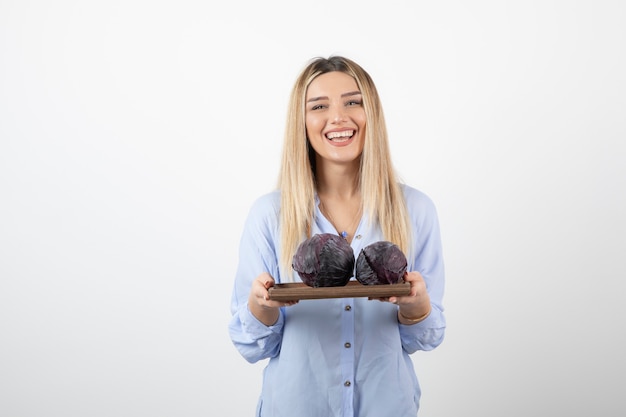 Image of a smiling pretty woman model standing and holding cabbage.
