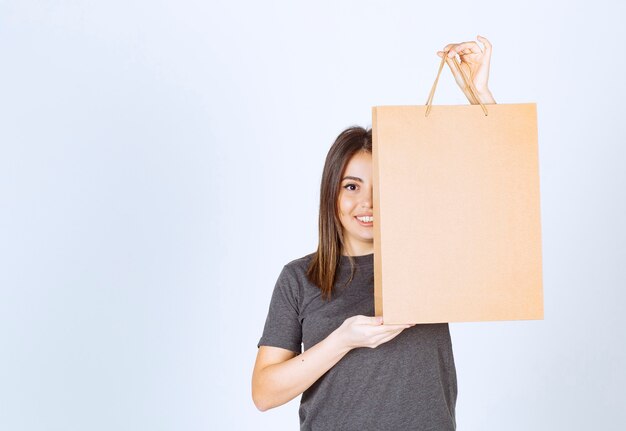 Image of smiling woman holding a paper bag and posing.