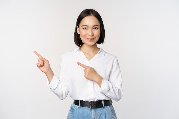 Image of smiling young office lady asian business entrepreneur pointing fingers left showing client info chart of banner aside on copy space white background