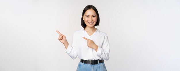 Image of smiling young office lady asian business entrepreneur pointing fingers left showing client info chart of banner aside on copy space white background