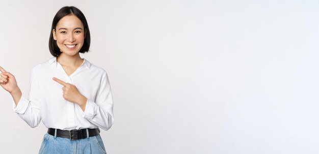 Image of smiling young office lady asian business entrepreneur pointing fingers left showing client info chart of banner aside on copy space white background