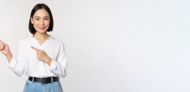 Изображение улыбающейся молодой офисной леди азиатского бизнес-предпринимателя, указывающей пальцем влево, показывая клиенту
