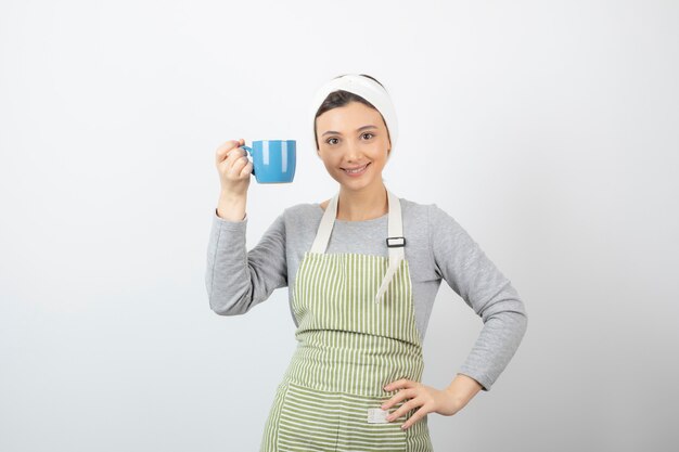 Image of a smiling young woman in apron holding a blue cup