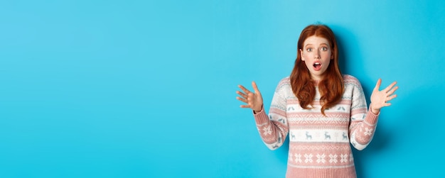 Image of startled redhead woman staring at camera with hands spread sideways catching something stan