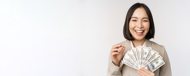 돈을 들고 성공적인 사업가의 이미지 현금 달러를 가진 아시아 기업 여성이 흰색 배경 위에 서서 웃고 웃고
