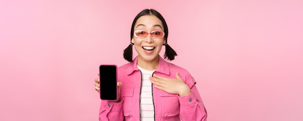 Image of surprised girl showing mobile phone app screen smartphone display application interface sta