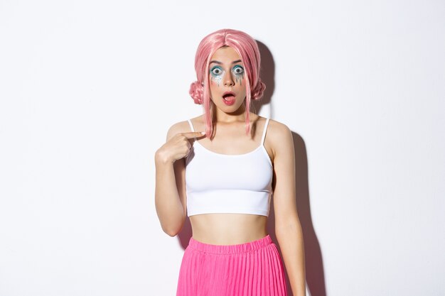 Image of surprised silly girl with pink anime hair and bright makeup, pointing at herself with opened mouth