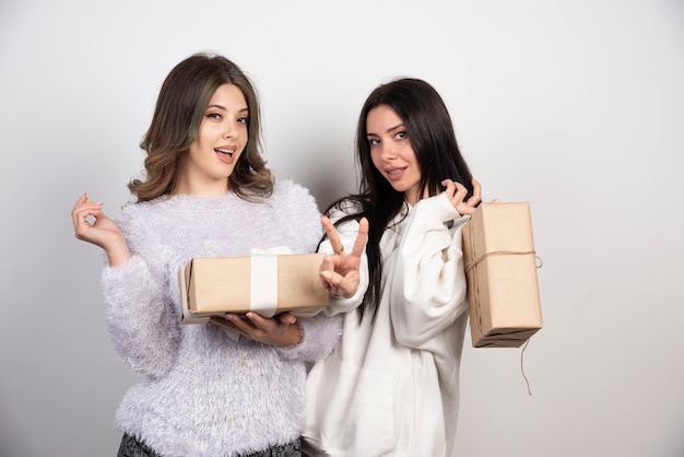 Image of two best friends standing together and holding gift boxes .