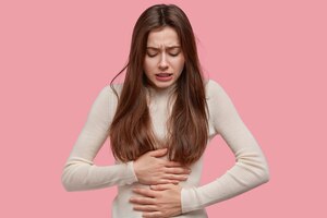Image of unhappy woman suffers from stomachache after eating spoiled food, feels discomfort in belly, has disorder