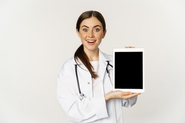 Image of woman doctor female healthcare worker showing online medical website digital tablet screen ...