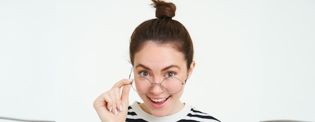 Free photo image of woman in glasses looks surprised takes off eyewear looks amazed says wow impressed by