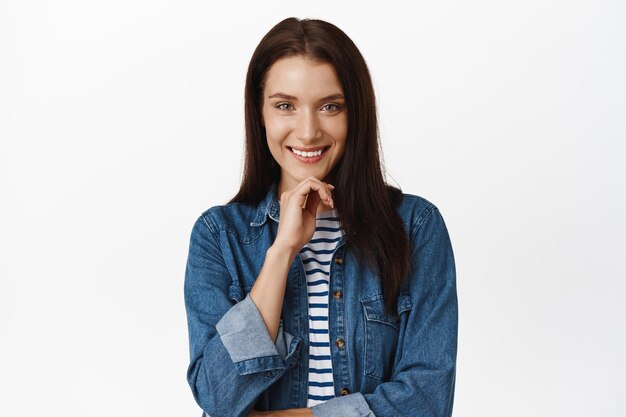 Image of woman thinking, making decision, planning investment, smiling pleased, listening to suggestion with thoughtful face expression, standing over white background