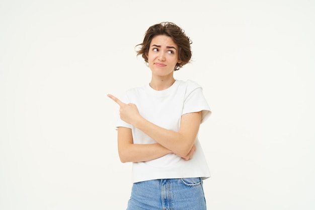 Image of woman with sceptical expression pointing finger left showing advertisement with doubtful