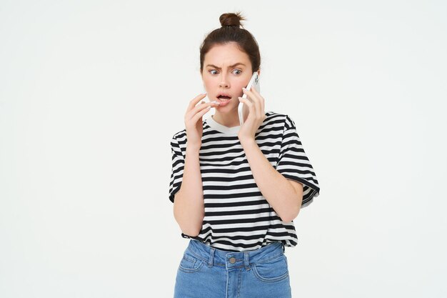 Image of woman with shocked face looks confused while chats over the phone listens to person on