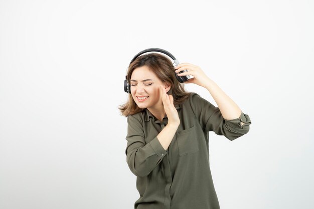 Изображение молодой привлекательной женщины в наушниках, слушающей песню. Фото высокого качества