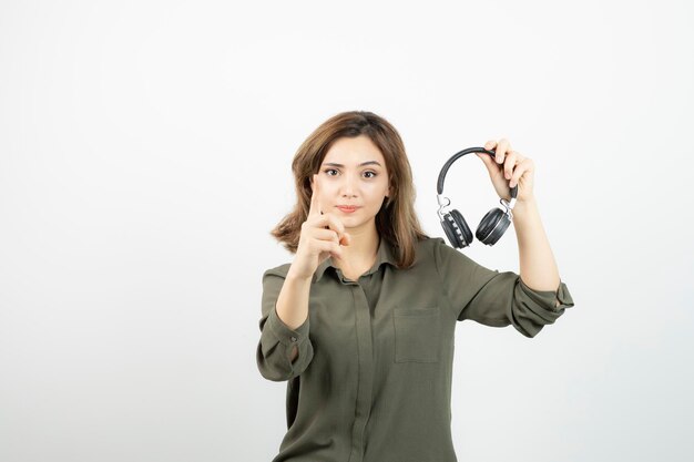 Image of young attractive woman holding black headphones. High quality photo