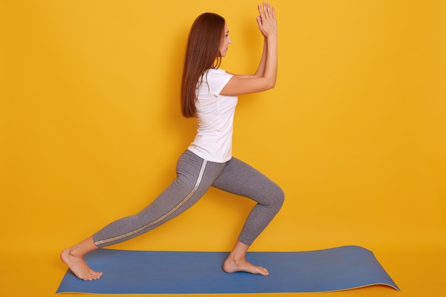 Image of young beautiful woman yoga posing isalated over yellow studio