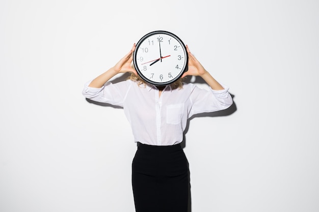 Image of young business woman standing isolated over white wall covering face with clock.