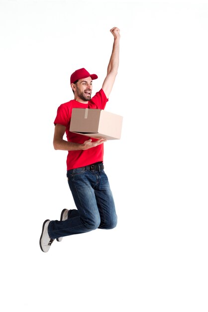 Изображение молодой доставщик прыгает и держит коробку