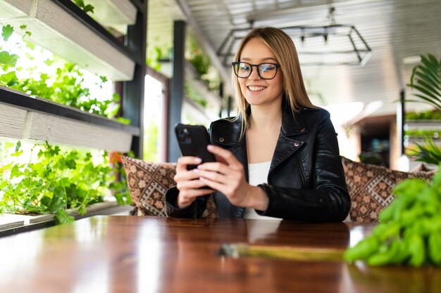 카페에서 전화로 SMS를 읽는 젊은 여성의 이미지