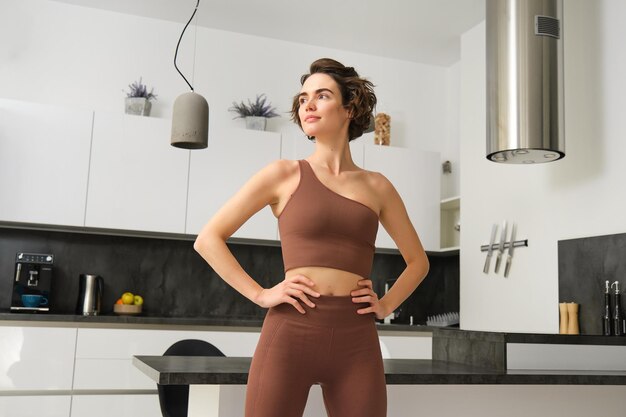 O を見て自宅でパワー ポーズ トレーニングに立っているスポーツウェアを着た若いフィット女性フィットネス女の子の画像