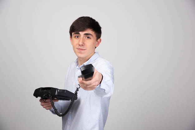 Free photo image of a young guy model standing and offering old black handset