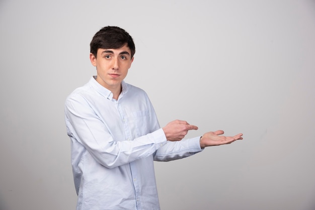 Image of a young guy model standing and pointing at an opened palm