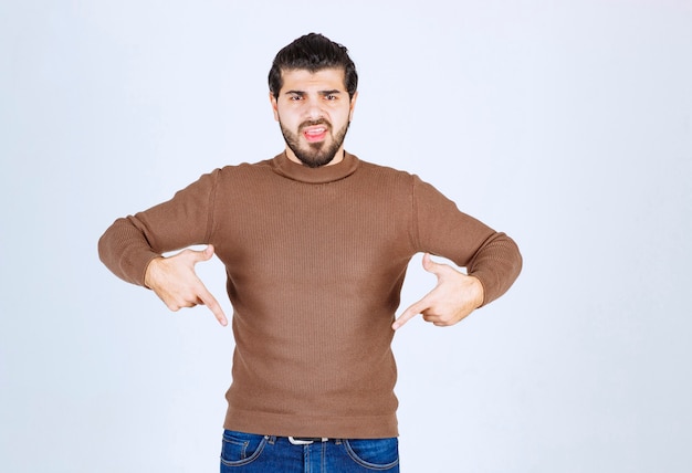 Free photo image of a young handsome man model standing and pointing down. high quality photo