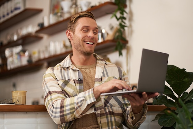 Free photo image of young man in coffee shop connects to video call talking online chats with friends via