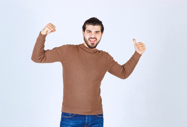 Image of a young man model standing and showing backwards with a thumb . High quality photo