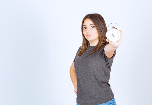 Image of a young nice woman model showing an alarm clock.