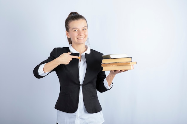 Foto gratuita immagine di giovane studente in possesso di libri e in piedi su bianco.