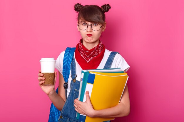 그녀의 보고서에 대해 생각하는 동안 클립 보드와 커피 컵을 들고 젊은 학생의 이미지 실망을 느끼고, 기분이 좋지 않은, 유행의 옷을 입고 그녀의 에세이에 대한 주제를 싫어합니다.