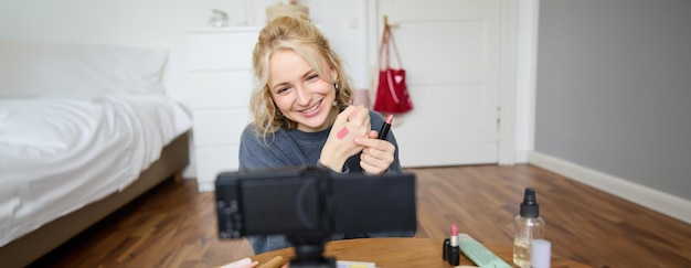 Foto gratuita immagine di una giovane e elegante blogger che registra un video di stile di vita di bellezza di lei che sceglie il miglior rossetto