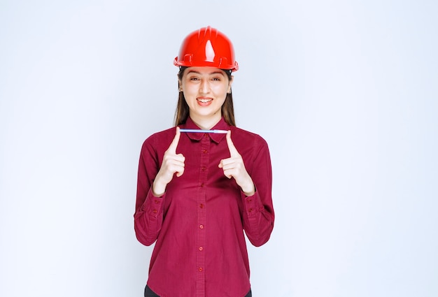 Image of young woman in crash helmet holding pencil and posing . 